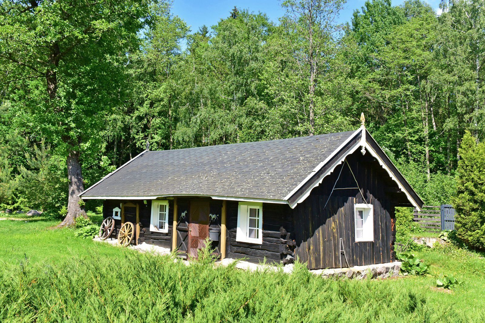 Žemas juodų rąstų svečių namelis su baltais langais